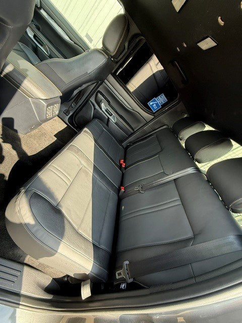 Rear bench of the Ford Ranger 2-Seat Commercial rear seat conversion viewed through the open rear door, showing the seat cushion, backrest and belt buckles
